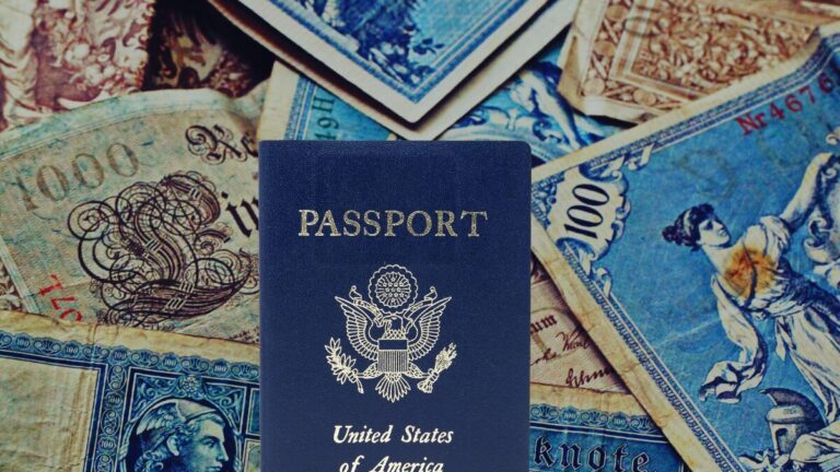 Passport, and international currency scattered across desk with travel documents