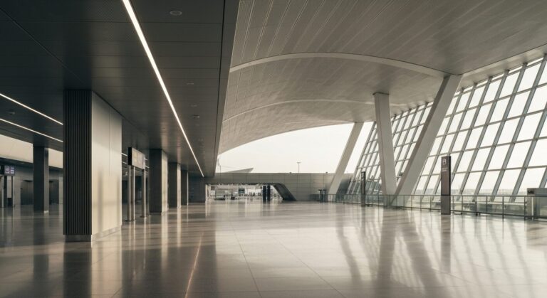 Empty modern airport terminal with architectural design and polished floors, bathed in natural light.